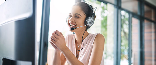 Smiling, helpful woman on headset and computer helping a customer