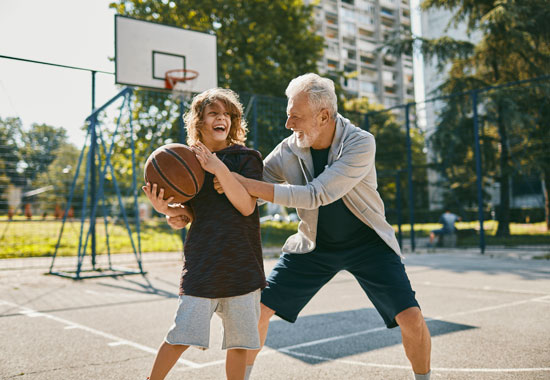 grandfather and grandson playing basketball outside together