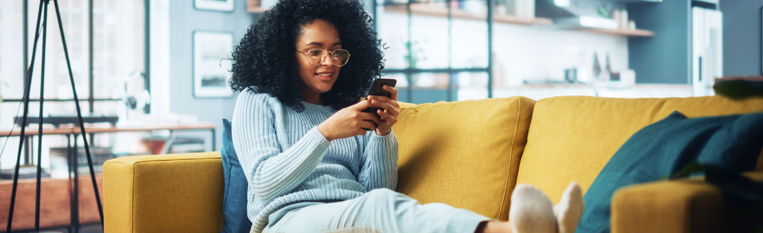 young female sitting on couch viewing her mobile phone
